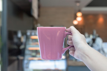 Woman hands holding coffee cup with blurred coffee shop