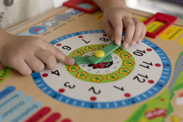 Little kid learning time with clock toy of Montessori.