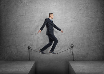 Businessman walking on drawn tightrope over the gap