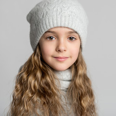 Portrait of a beautiful little girl with magnificent long hair on a gray background