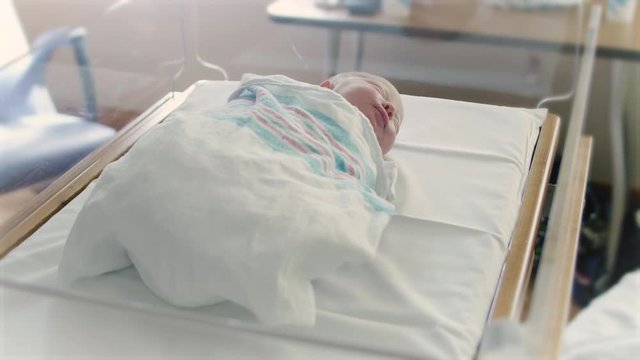 Blur to Focus on Cute Newborn Baby in Hospital Delivery Room Bed