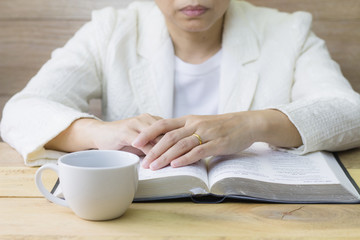  a woman reading the holy bible and a cup of coffee on wooden table