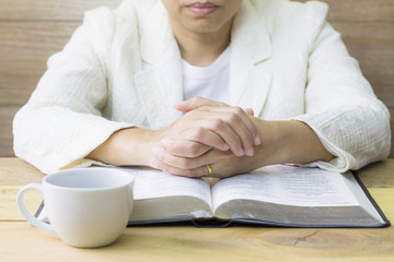  a woman reading the holy bible and a cup of coffee on wooden table