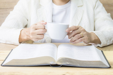  a woman reading the holy bible and a cup of coffee on wooden table