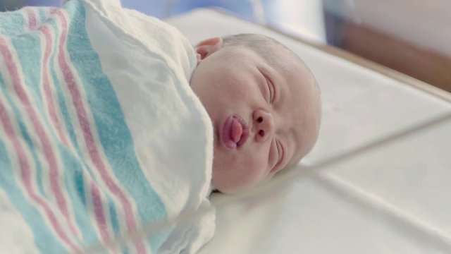 Close Up Newborn Baby Making Funny Faces in Bright Hospital Delivery Room
