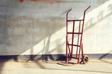 Red empty sack barrow or hand truck dolly  Beside old walls back - obrazy, fototapety, plakaty