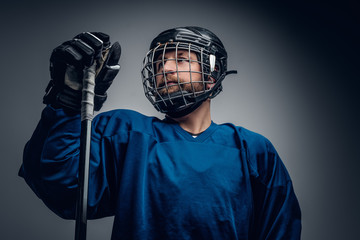 Fototapeta premium A bearded ice-hockey player in safety helmet holds the gaming st