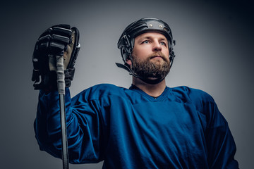 Fototapeta premium Bearded ice-hockey player in safety helmet holds the gaming stic