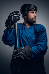 Bearded ice-hockey player in safety helmet holds the gaming stic