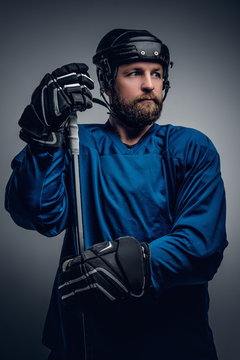 Bearded ice-hockey player in safety helmet holds the gaming stic