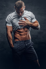Young athletic male shows six pack ABS.
