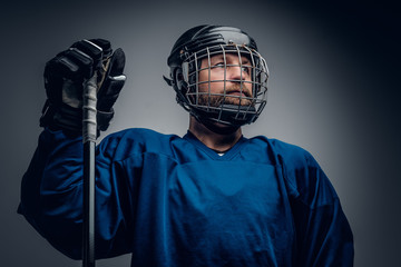 Naklejka premium Bearded ice-hockey player in safety helmet holds the gaming stic