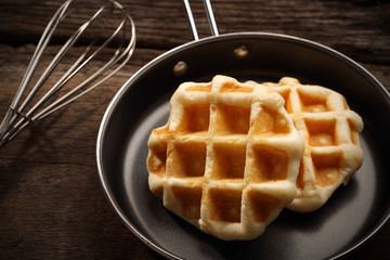 Close up baked waffles inside the teflon pan with hand mixer kitchen on wood background