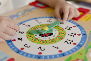 Little kid learning time with clock toy of Montessori.
