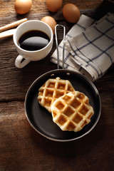 Fresh Waffles and hot coffee for breakfast set with eggs and wood background