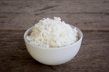 raw jasmine rice in white bowl on wooden table top