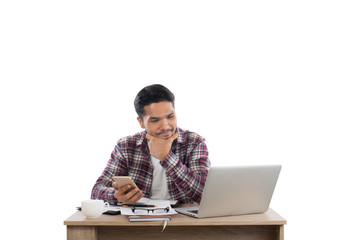 Thoughtful young man  looking at laptop while sitting at his work place.