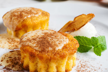Close-up of sweet cupcakes with topping and chocolate. Tasty dessert of pumpkin muffins with pear slice and ice-cream ball. Confectionery, pastry, restaurant menu concept