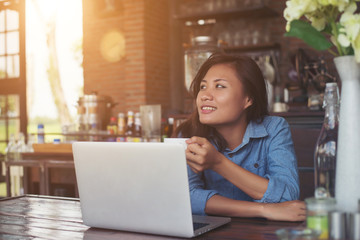 Pretty young hipster woman sitting in a cafe with her laptop, lo