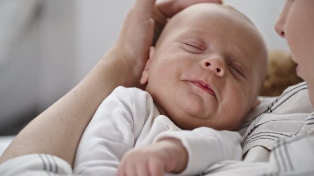 Peaceful infant boy tightly sleeping in mothers arms 