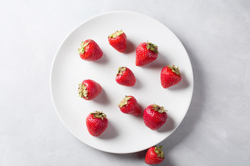 Strawberry on a white plate. Fresh strawberry on a light background . Red strawberry. Loosely laid strawberries in different positions. Copyspace. Valentine's Day background.