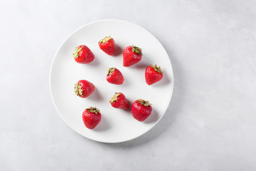 Strawberry on a white plate. Fresh strawberry on a light background . Red strawberry. Loosely laid strawberries in different positions. Copyspace. Valentine's Day background.