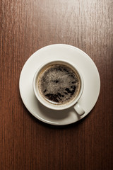 Top view of a paper cup of black coffee on wooden table