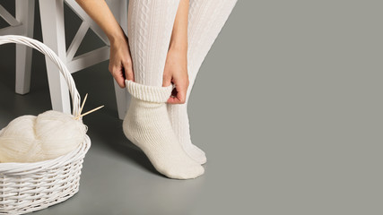 Female feet in white knitted stockings and socks near the basket