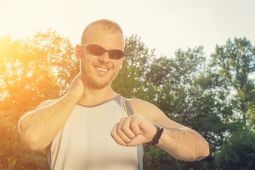 Jogger making a pause in the park and checking his running time.