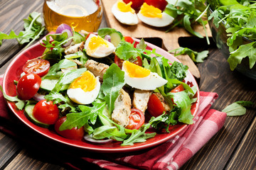 Fresh salad with chicken, tomatoes, eggs and arugula on plate