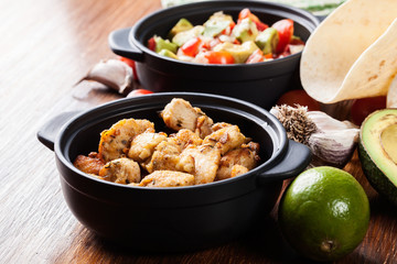 Ingredients ready for preparing chicken tacos with salsa made from avocado, tomatoes, and chilli peppers