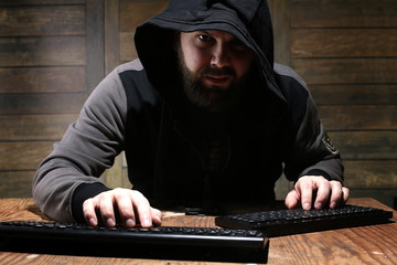 hacker in the black hood in a room with wooden walls