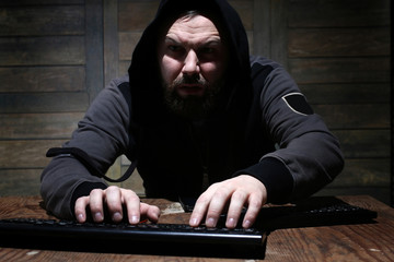 hacker in the black hood in a room with wooden walls