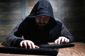 hacker in the black hood in a room with wooden walls