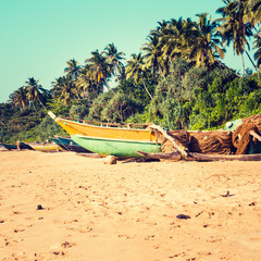 Naklejka na ściany i meble Fishing boats on a tropical beach with palm trees in the backgro