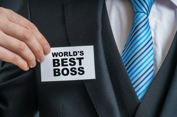 Businessman in suit is showing label that He is worlds best boss ever.