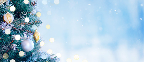 Decorated Christmas tree with bright bokeh on winter blue snowy background. Christmas border. 