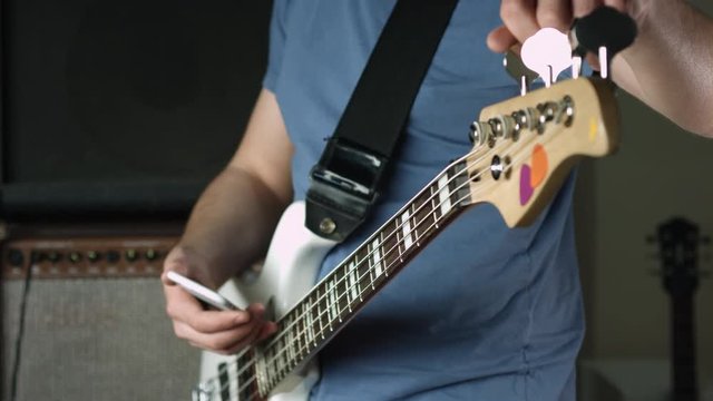 Guy tune bass guitar with smartphone app