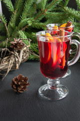 Hot Mulled wine with cinnamon and christmas tree, cone on black slate dish.