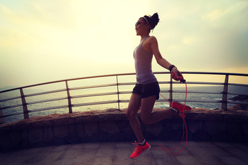 young fitness woman skipping rope at seaside