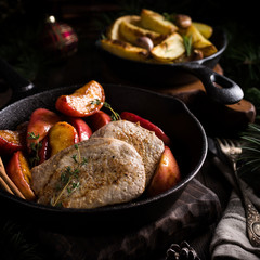 Delicious Christmas themed dinner table with roasted pork steak, caramelized apples and baked potatoes. Holiday concept.