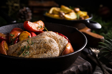Delicious Christmas themed dinner table with roasted pork steak, caramelized apples and baked potatoes. Holiday concept.
