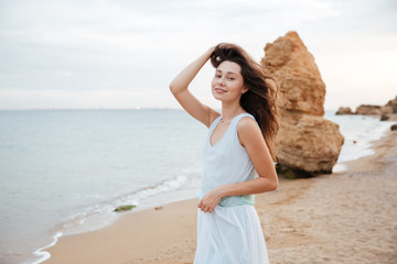 Fototapeta na wymiar Happy woman in white dress standing on the beach
