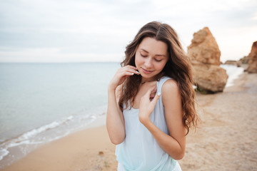 Fototapeta na wymiar Cute young woman with long hair standing on the beach