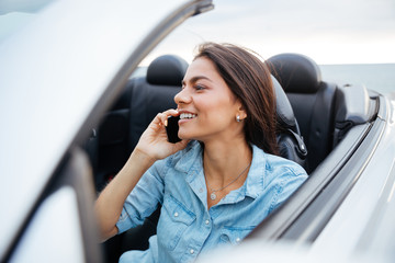 Happy woman driving car and talking on mobile phone