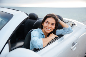 Cheerful smiling brunette woman resting inside her cabriolet