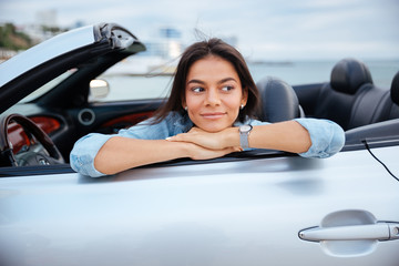 Smiling young woman sitting inside her convertible car