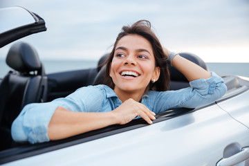 Smiling brunette woman resting in her cabriolet