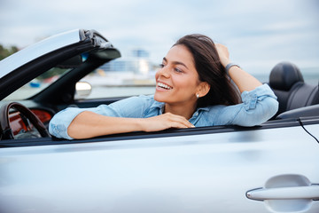 Cheerful smiling brunette woman resting in her cabriolet