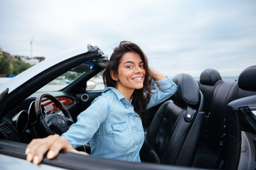 Cheerful smiling brunette woman resting in her cabriolet